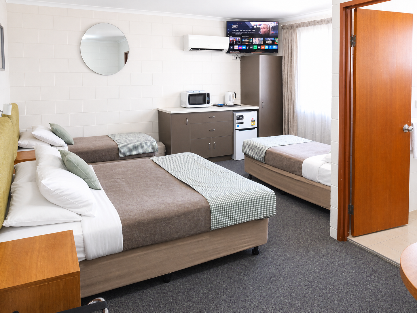 Cozy twin bedroom with TV, microwave, and simple decor.