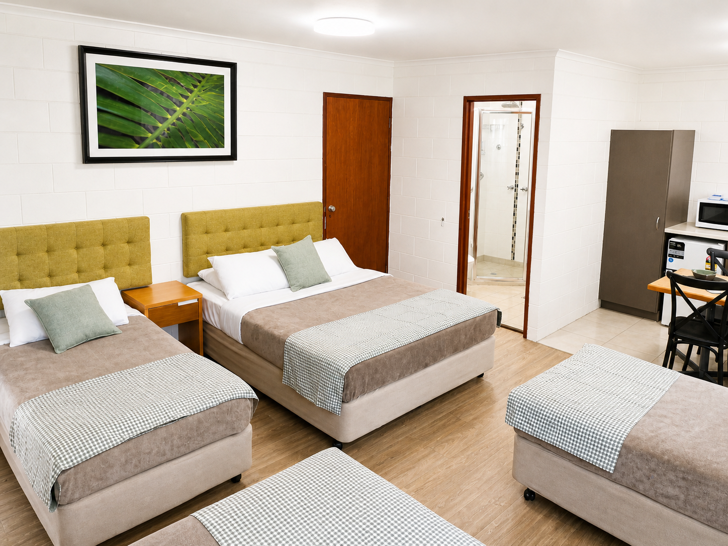 Bright hotel room with three beds and modern decor.